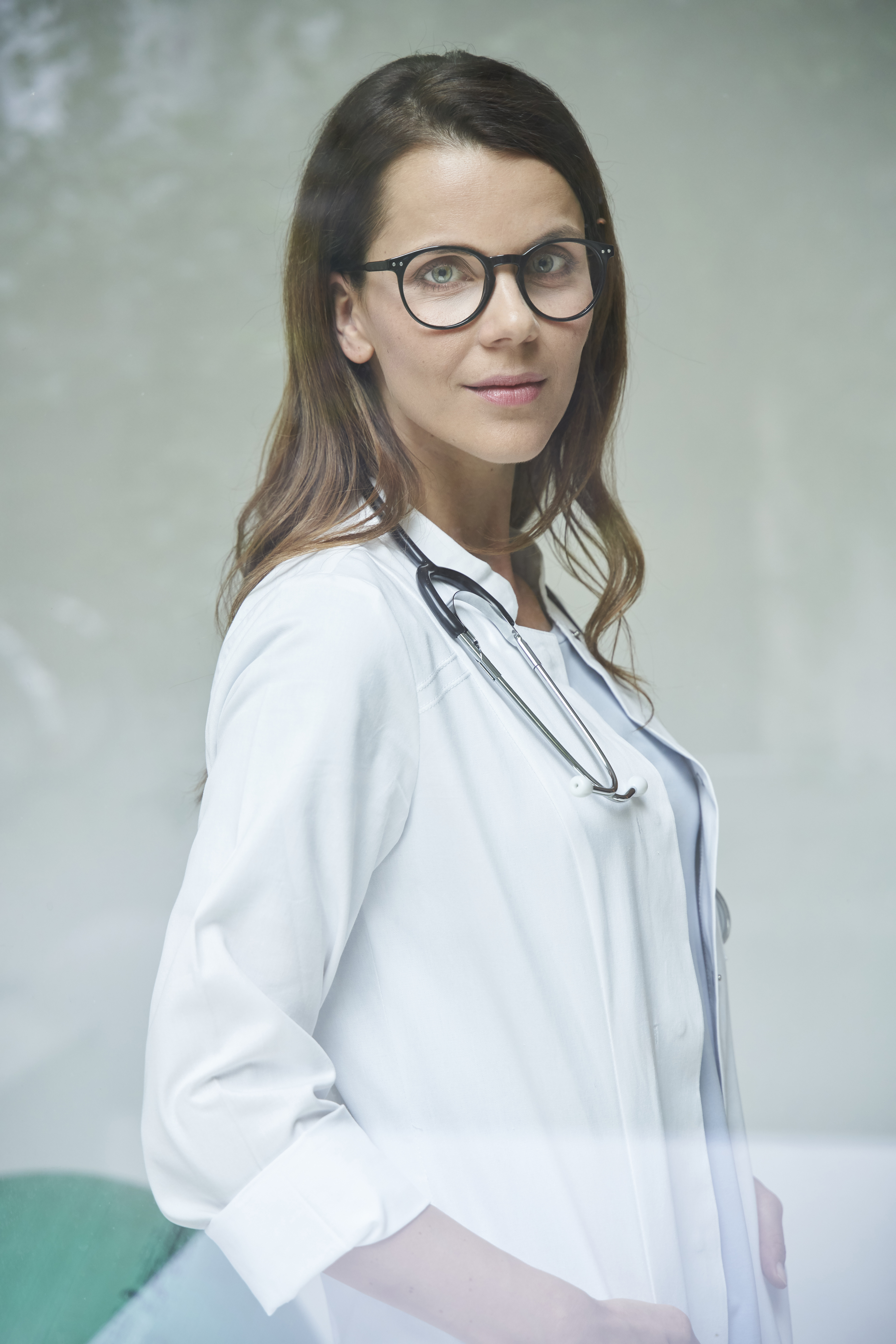 Portrait of confident female doctor behind windowpane
